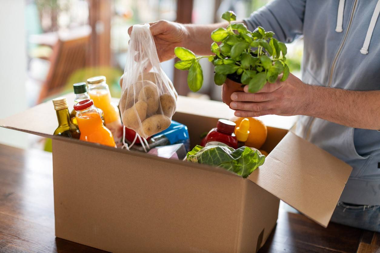 a decorative picture showing a man picking groceries out of a delivery box